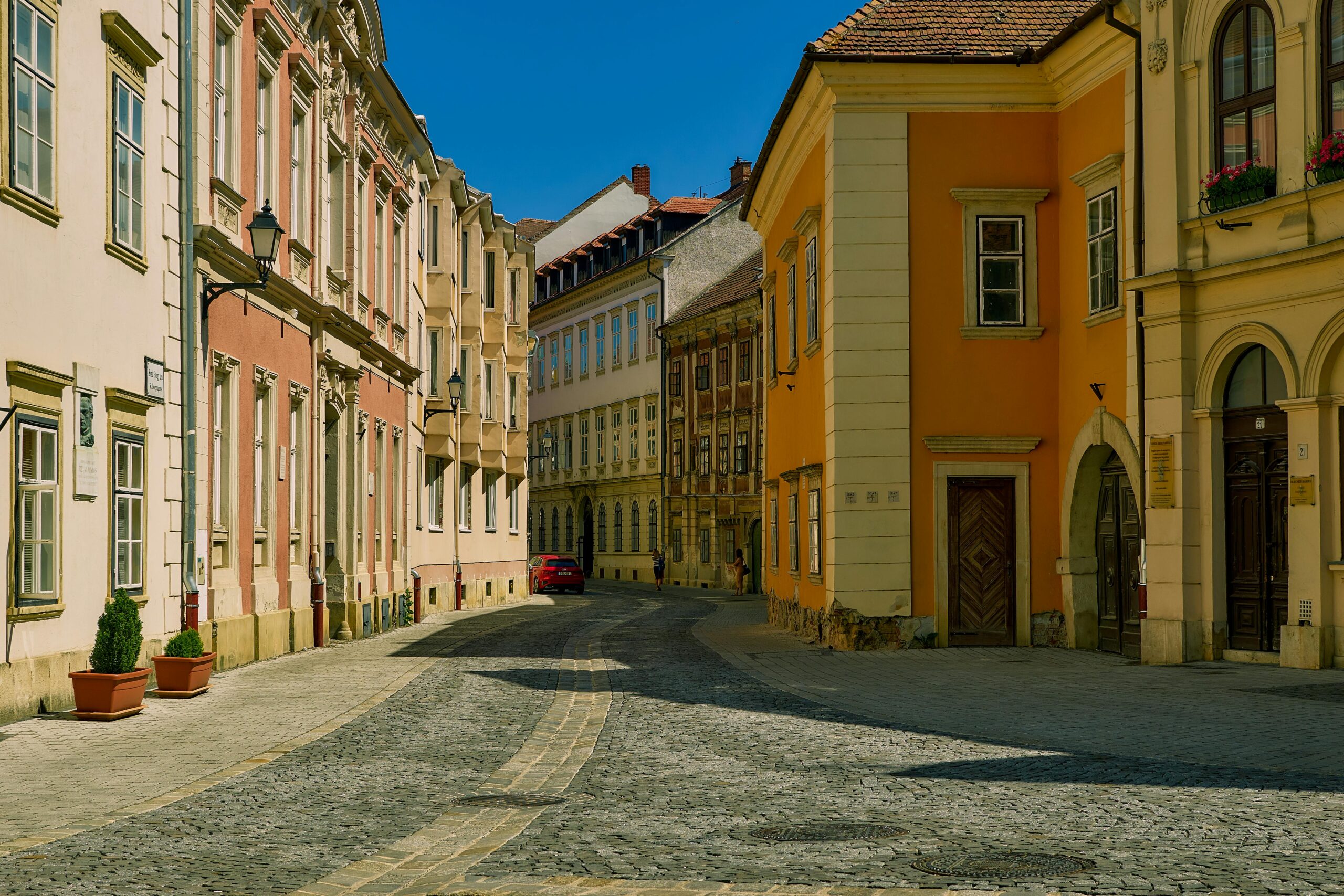 A peaceful street in historic Sopron, Hungary featuring colorful buildings under a clear blue sky.